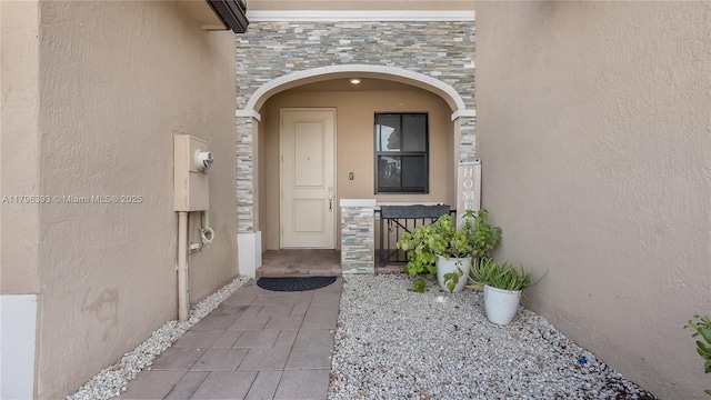 doorway to property with stone siding and stucco siding