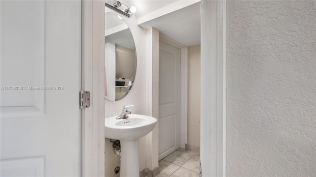 bathroom with tile patterned floors, a sink, and a textured wall