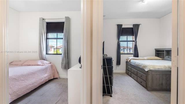 bedroom featuring multiple windows, light carpet, and baseboards