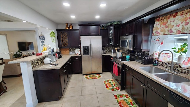 kitchen with a peninsula, backsplash, stainless steel appliances, and a sink