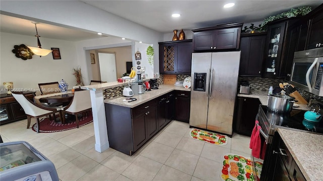 kitchen with a peninsula, stainless steel appliances, pendant lighting, tasteful backsplash, and recessed lighting