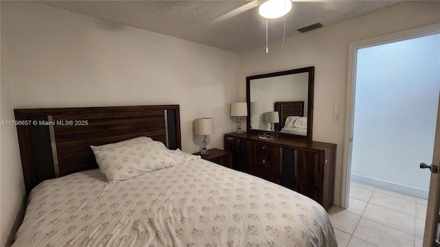 bedroom with light tile patterned floors, a textured ceiling, visible vents, and a ceiling fan