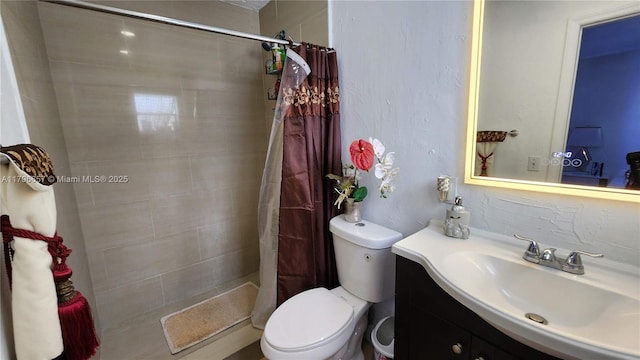 bathroom with toilet, tiled shower, and vanity