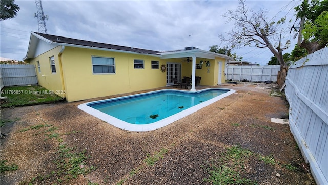 rear view of property featuring stucco siding, ceiling fan, and a fenced backyard