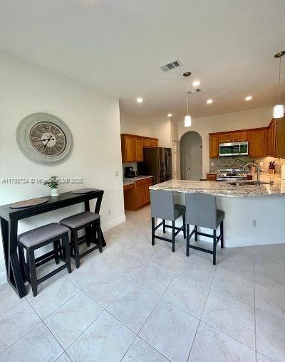 kitchen featuring brown cabinets, arched walkways, visible vents, and appliances with stainless steel finishes