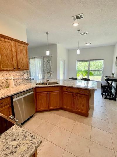kitchen featuring a wealth of natural light, brown cabinets, a sink, and dishwasher