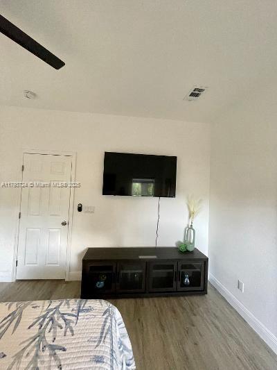 bedroom with baseboards, ceiling fan, visible vents, and wood finished floors