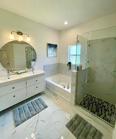 bathroom with a stall shower, recessed lighting, marble finish floor, a garden tub, and double vanity