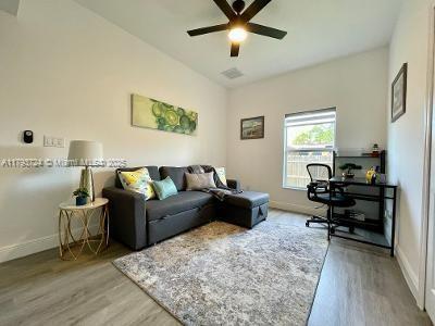 living area with ceiling fan, baseboards, visible vents, and wood finished floors