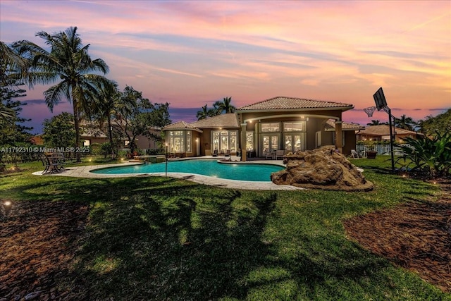 pool at dusk with a yard, fence, a patio, and french doors