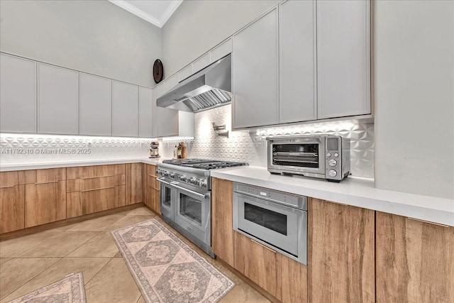 kitchen with under cabinet range hood, range with two ovens, modern cabinets, crown molding, and oven