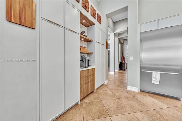 kitchen with modern cabinets, built in fridge, light tile patterned flooring, open shelves, and light countertops