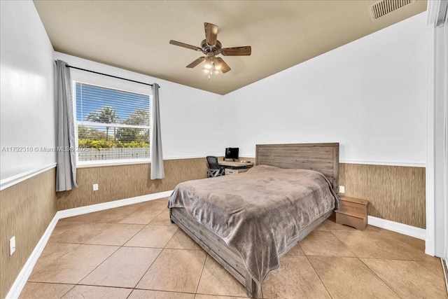 tiled bedroom with a ceiling fan, visible vents, baseboards, wainscoting, and wooden walls
