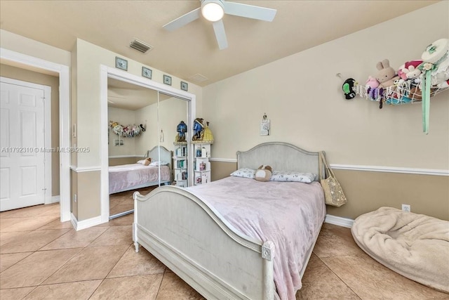 tiled bedroom with a closet, visible vents, baseboards, and ceiling fan