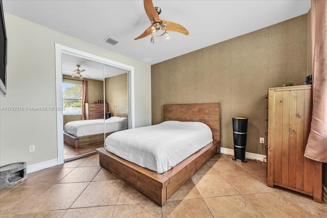 bedroom with a closet, light tile patterned flooring, visible vents, a ceiling fan, and baseboards