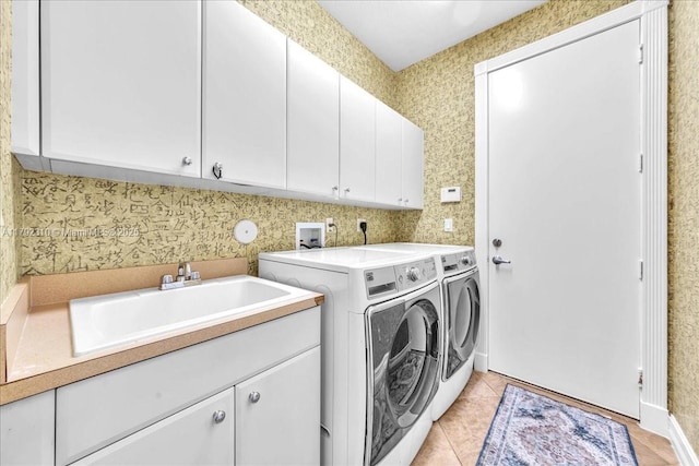 laundry room featuring a sink, cabinet space, washer and dryer, light tile patterned floors, and wallpapered walls