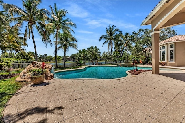 view of pool with a patio area, a pool with connected hot tub, and fence