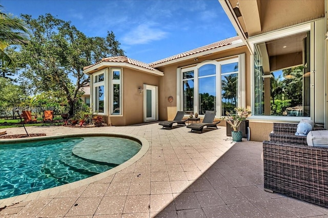 back of house featuring a patio, a tile roof, stucco siding, and an outdoor pool