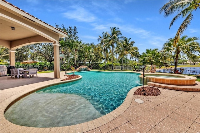 view of pool with a pool with connected hot tub, fence, and a patio