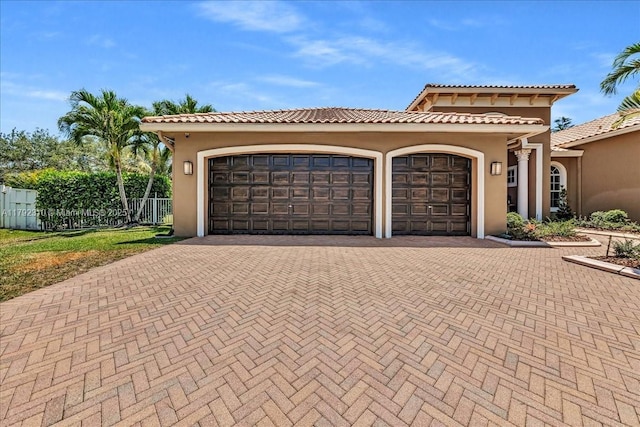 mediterranean / spanish-style house with fence, stucco siding, and decorative driveway