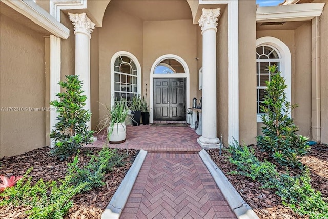 entrance to property with covered porch and stucco siding