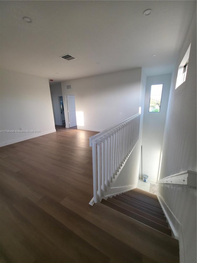 staircase featuring baseboards, visible vents, and wood finished floors