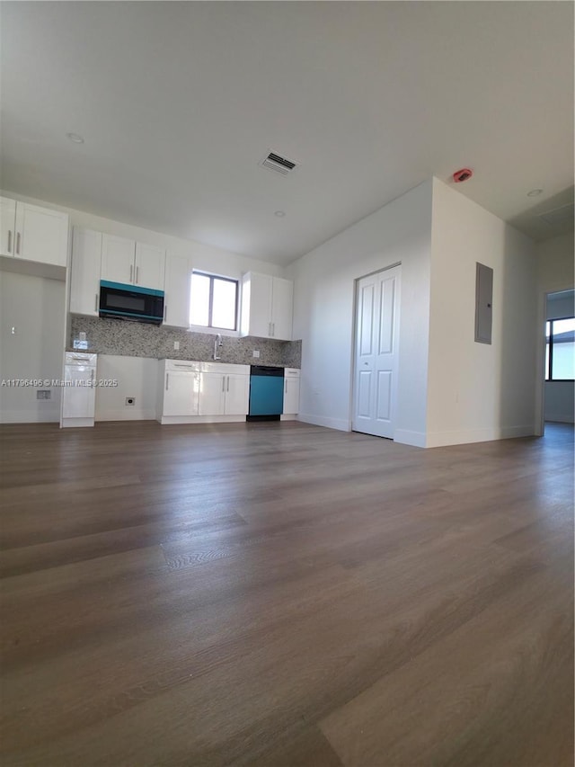 unfurnished living room featuring visible vents, baseboards, dark wood-style floors, and a sink