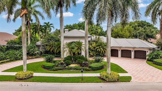 mediterranean / spanish-style house with stucco siding, a tiled roof, and decorative driveway