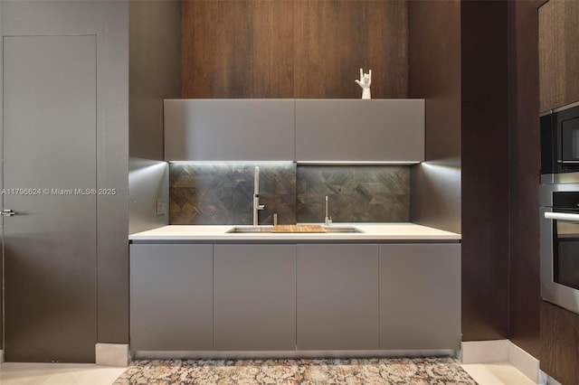 kitchen with a sink, stainless steel oven, black microwave, decorative backsplash, and modern cabinets