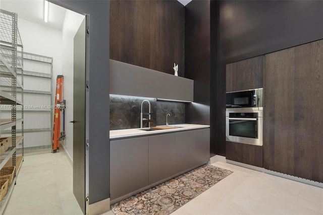 kitchen featuring built in microwave, modern cabinets, stainless steel oven, and a sink