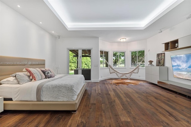 bedroom with a raised ceiling, recessed lighting, wood-type flooring, and access to exterior