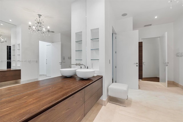 full bath with an inviting chandelier, visible vents, a sink, built in shelves, and double vanity