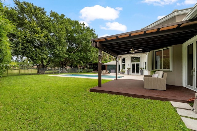 view of yard featuring a ceiling fan, french doors, a fenced in pool, a deck, and a fenced backyard