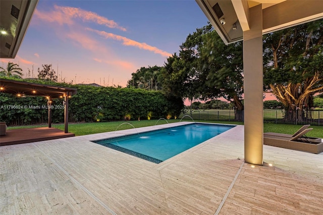 pool at dusk featuring a lawn, a wooden deck, a fenced in pool, and a fenced backyard