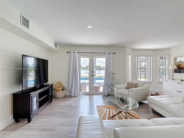 17931 NW 85th Ave, Hialeah, FL 33015 - living room featuring light wood-style flooring, healthy amount of natural light, french doors, and a textured ceiling