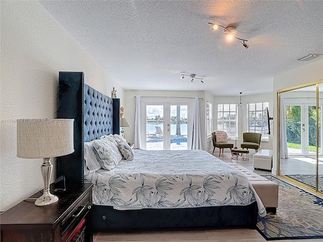 17931 NW 85th Ave, Hialeah, FL 33015 - bedroom with french doors, access to exterior, a textured ceiling, wood finished floors, and a textured wall