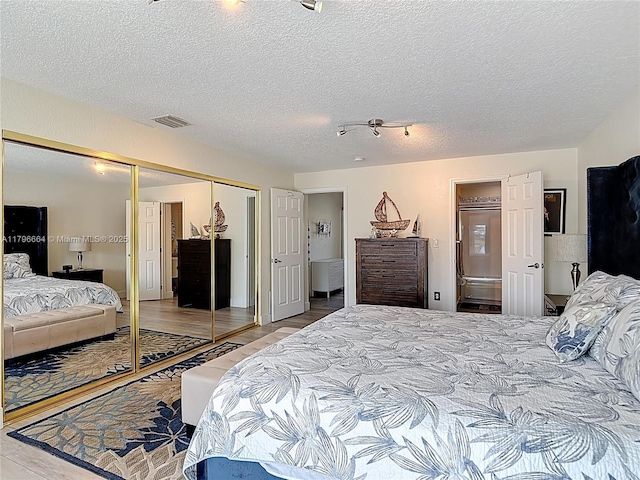 17931 NW 85th Ave, Hialeah, FL 33015 - bedroom with a closet, a textured ceiling, wood finished floors, and connected bathroom