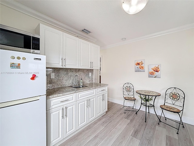 17931 NW 85th Ave, Hialeah, FL 33015 - kitchen with freestanding refrigerator, stainless steel microwave, crown molding, white cabinetry, and backsplash
