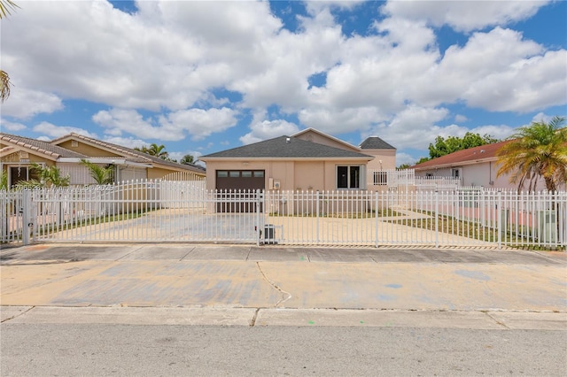 bungalow-style home with driveway, a fenced front yard, an attached garage, stucco siding, and a gate