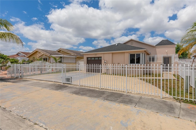 view of front facade featuring a gate, an attached garage, driveway, stucco siding, and a fenced front yard