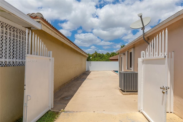 view of property exterior with central AC unit, stucco siding, fence, and a patio