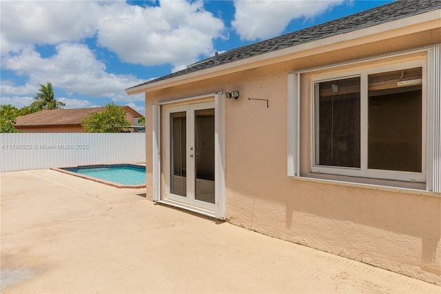 exterior space with french doors, stucco siding, fence, a patio area, and a fenced in pool