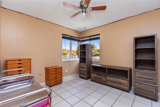 bedroom with ceiling fan, a textured ceiling, baseboards, and light tile patterned floors
