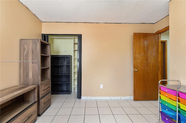 unfurnished bedroom featuring a textured ceiling and light tile patterned floors