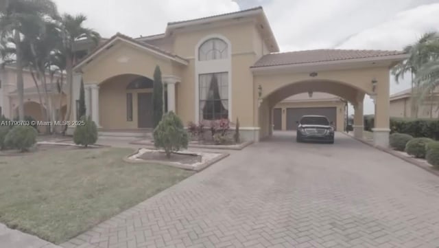 exterior space with a tile roof, an attached garage, stucco siding, and decorative driveway
