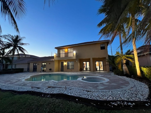 pool at dusk with a patio area, an in ground hot tub, and an outdoor pool