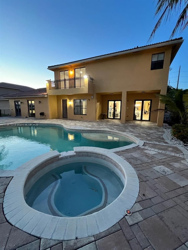 view of swimming pool with a patio area, french doors, and a pool with connected hot tub