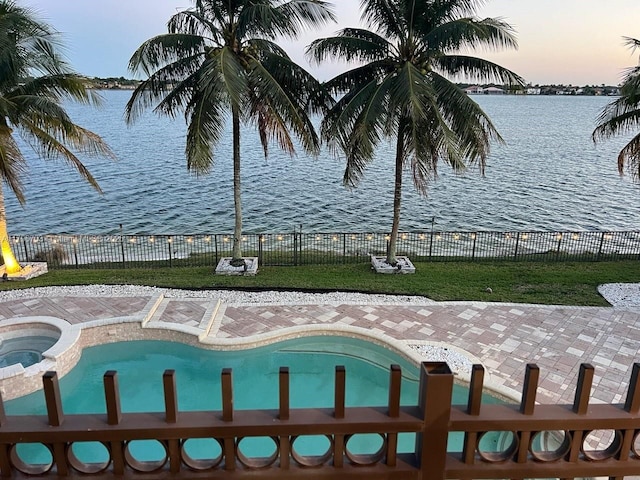 view of pool with a pool with connected hot tub, a water view, and fence