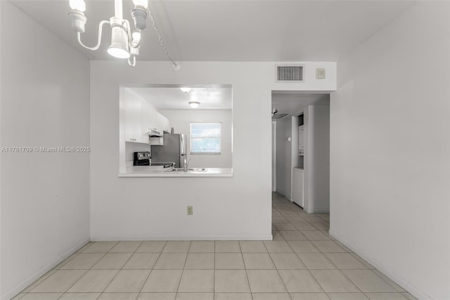 interior space with a notable chandelier, baseboards, light tile patterned floors, visible vents, and a sink