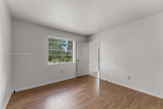 spare room with wood finished floors and baseboards